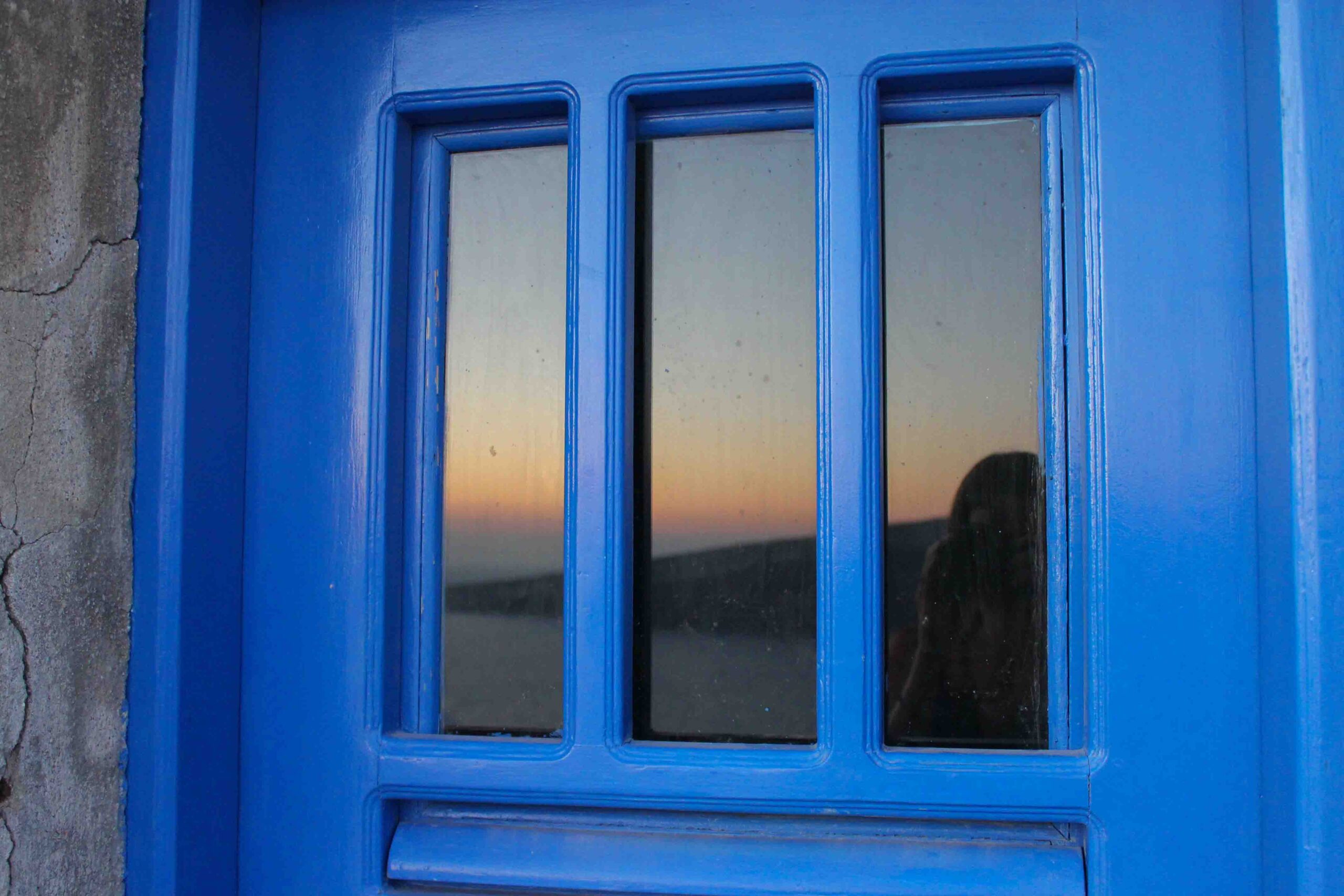 Sunset reflection in a blue door in Oia 